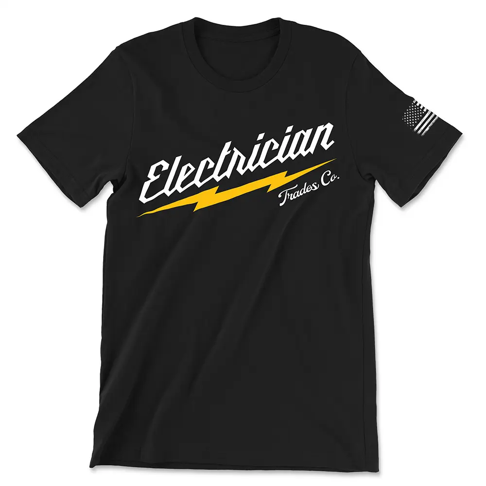 Black t-shirt that says "Electrician" in white with yellow lightening bolt beneath it and "Trades Co". in script below that. Features worn white American flag on left sleeve.