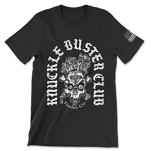 Black T-shirt with white design. "Knuckle Busters Club" I written in an curved lowercase n shape with a skull and crossbones with tools coming from the head in the center. Trades Co. is written bellow the skull. White American flag featured on the left sleeve.